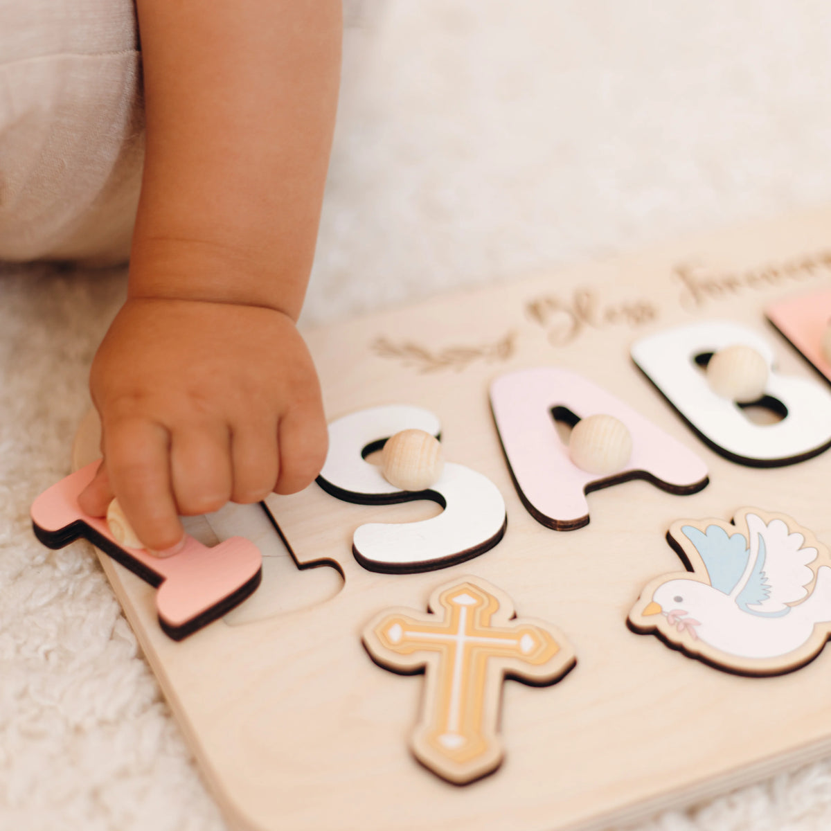 Baby's hands playing with removable pieces of Isabella baptism puzzle