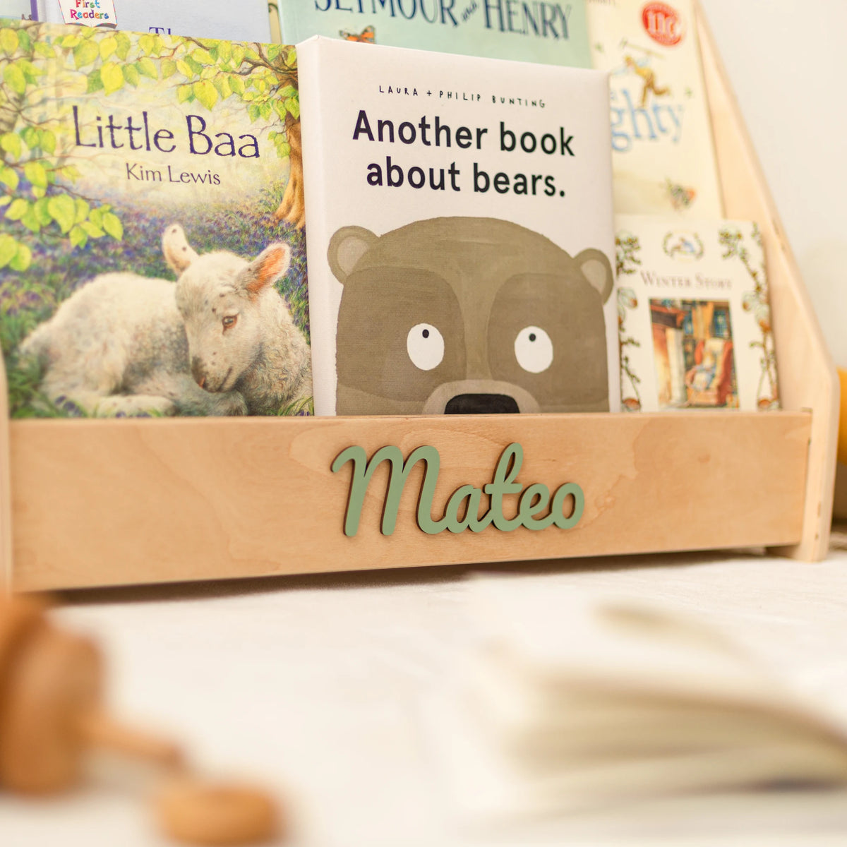 Light wood personalized bookshelf with name Mateo in green wooden letters and front-facing children's books