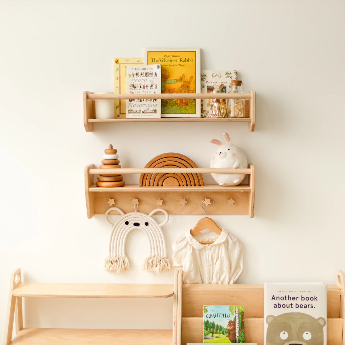 Light wood nursery wall shelves with children's clothes hanging from star-shaped wooden pegs