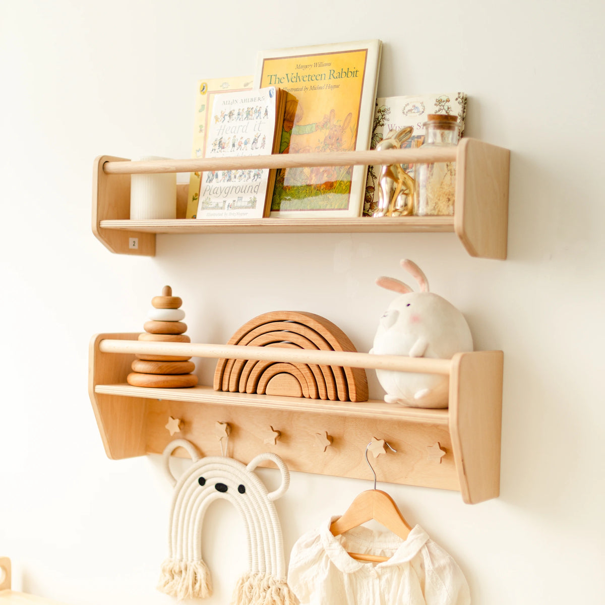 Two light wood wall shelves β a plain book ledge above a shelf with star-shaped pegs, styled with books and toys