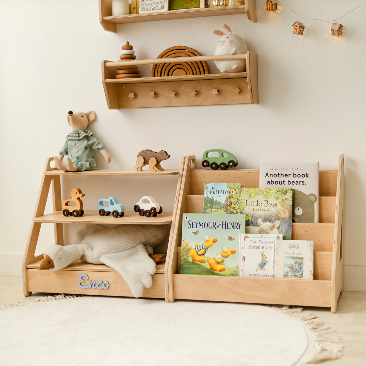 Light wood toy shelf and bookshelf set against a wall with a peg shelf, dolls, books and stuffed animals
