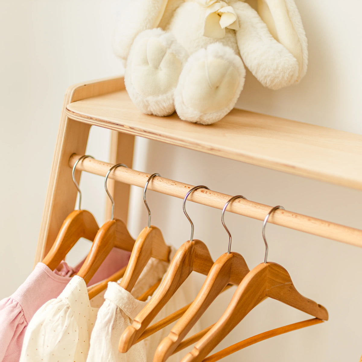 Close-up of the clothing rack's top shelf with soft baby booties and clothes hanging below
