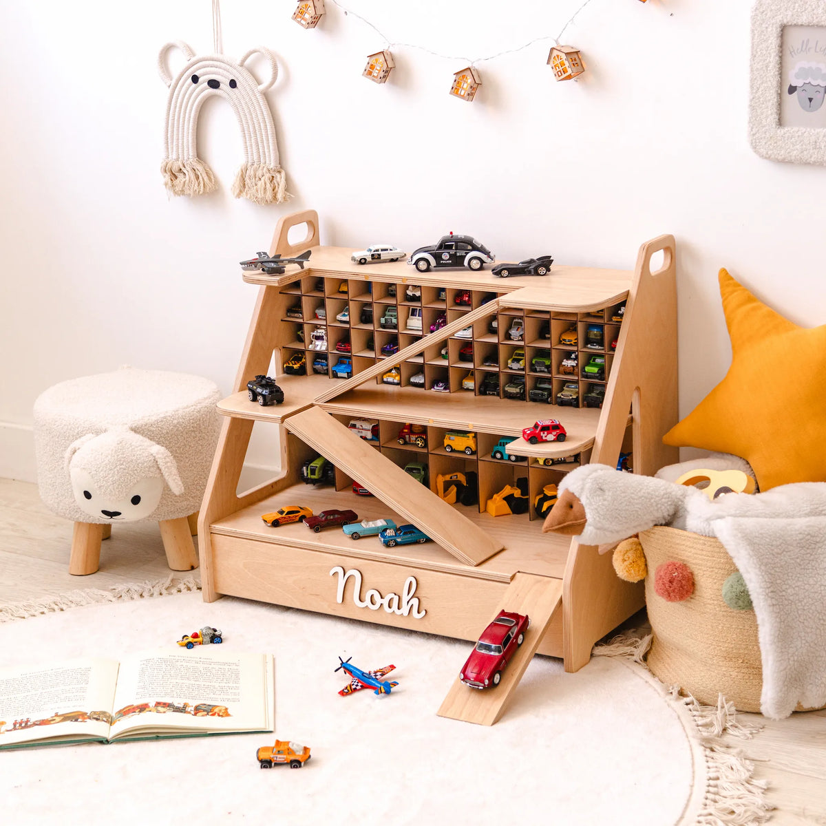Light wood toy car garage with the name Noah, holding a collection of toy cars in a playroom