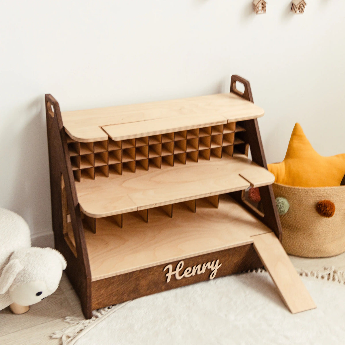 Dark wood toy car garage with three levels, 70 cells and a ramp next to plush toys