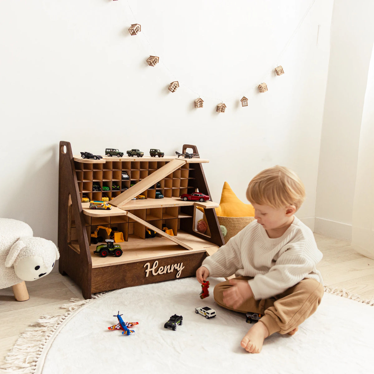 Boy playing on the floor with a dark wood personalized toy car garage with the name Henry