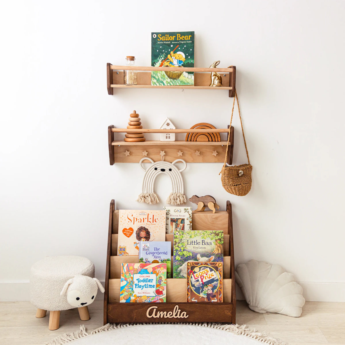 Light wood nursery wall shelves with toys mounted above a child's front-facing bookshelf