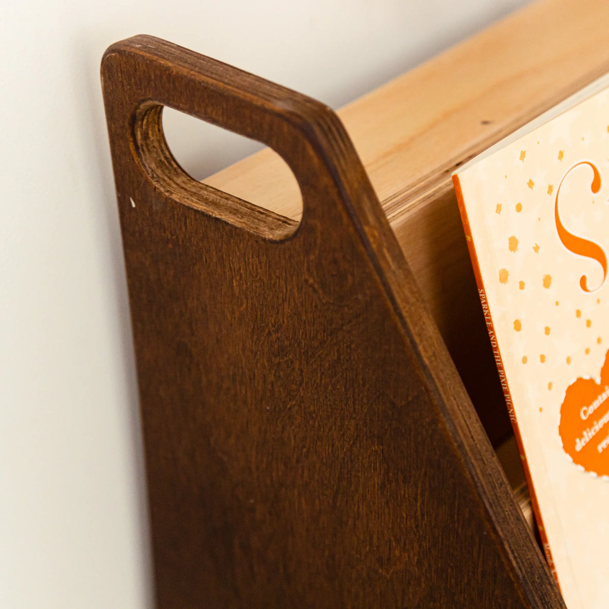Close-up of the dark wood bookshelf side panel with a cut-out carry handle