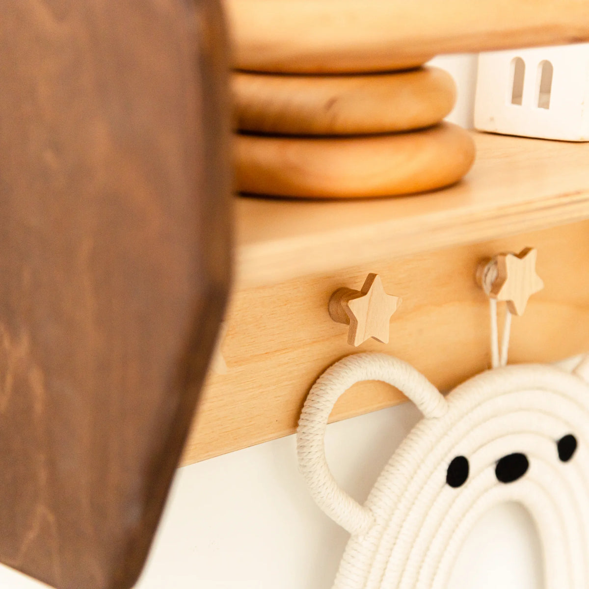 Close-up of a star-shaped wooden peg on a dark wood Montessori nursery wall shelf