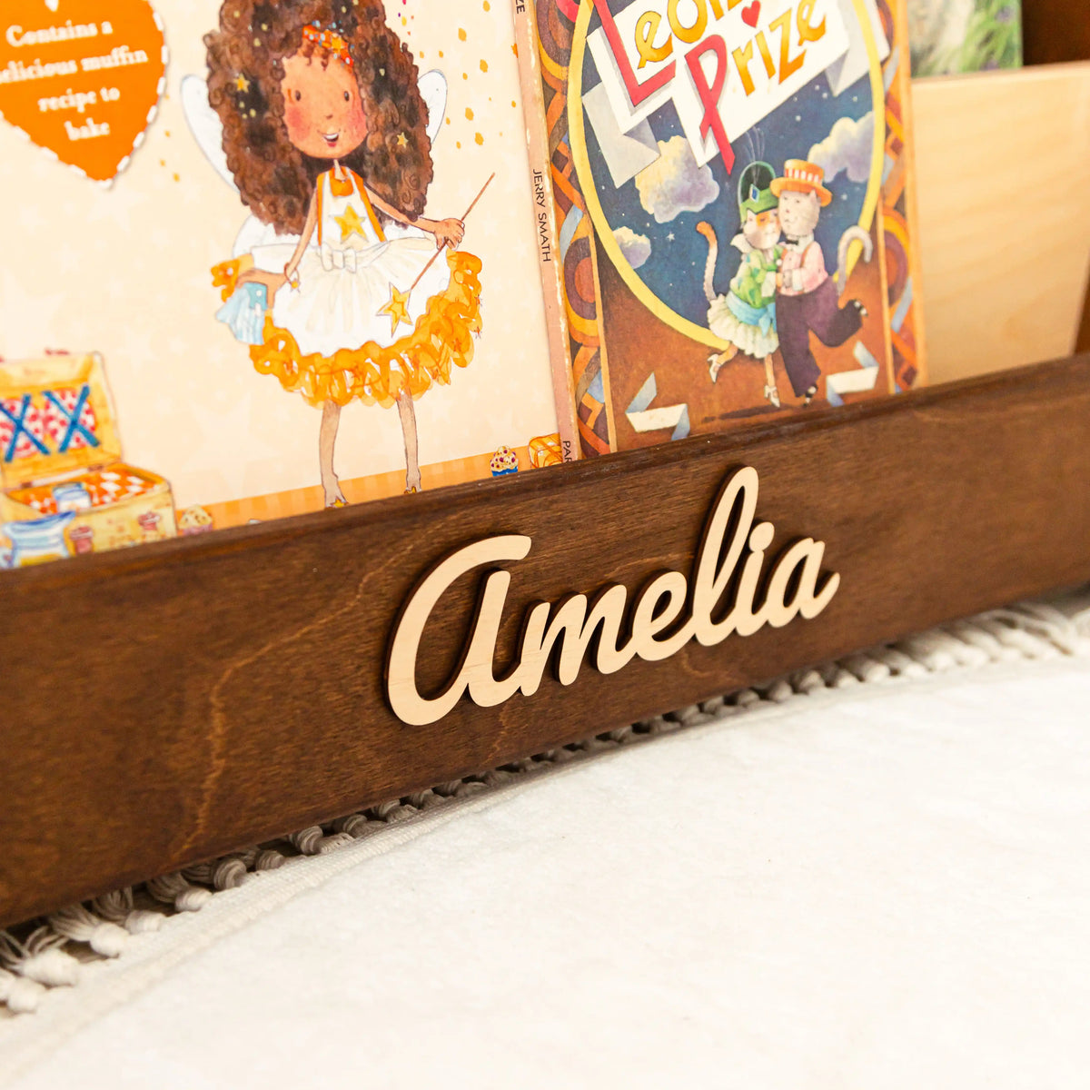 Dark wood personalized bookshelf with name Amelia in 3D wooden letters and colorful front-facing picture books