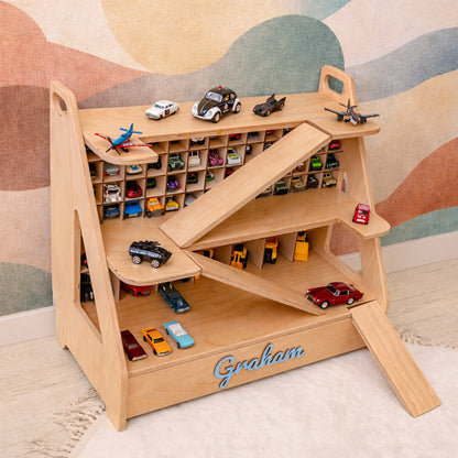 Light wood personalized toy car garage with name Graham in blue 3D letters, filled with toy cars in a kids playroom