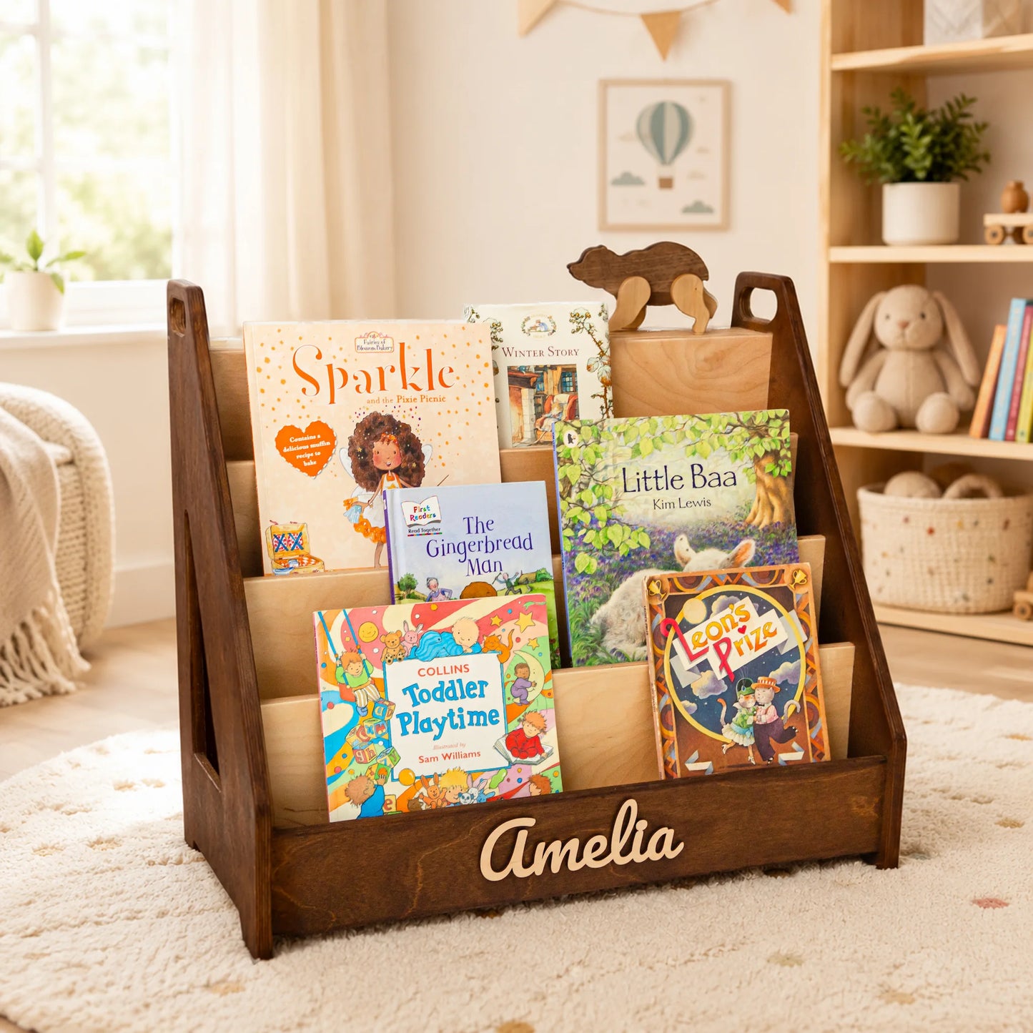 Dark wood Montessori front-facing bookshelf with name Amelia in a bright, sunlit kids room