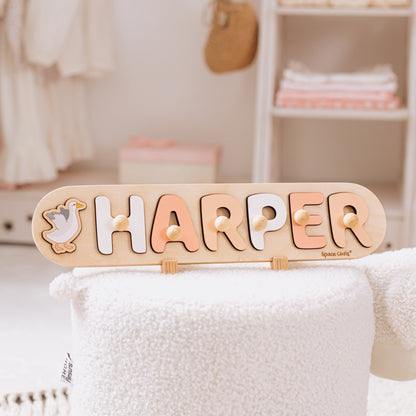 Wooden name puzzle with the name Harper and a swan piece standing on a shelf