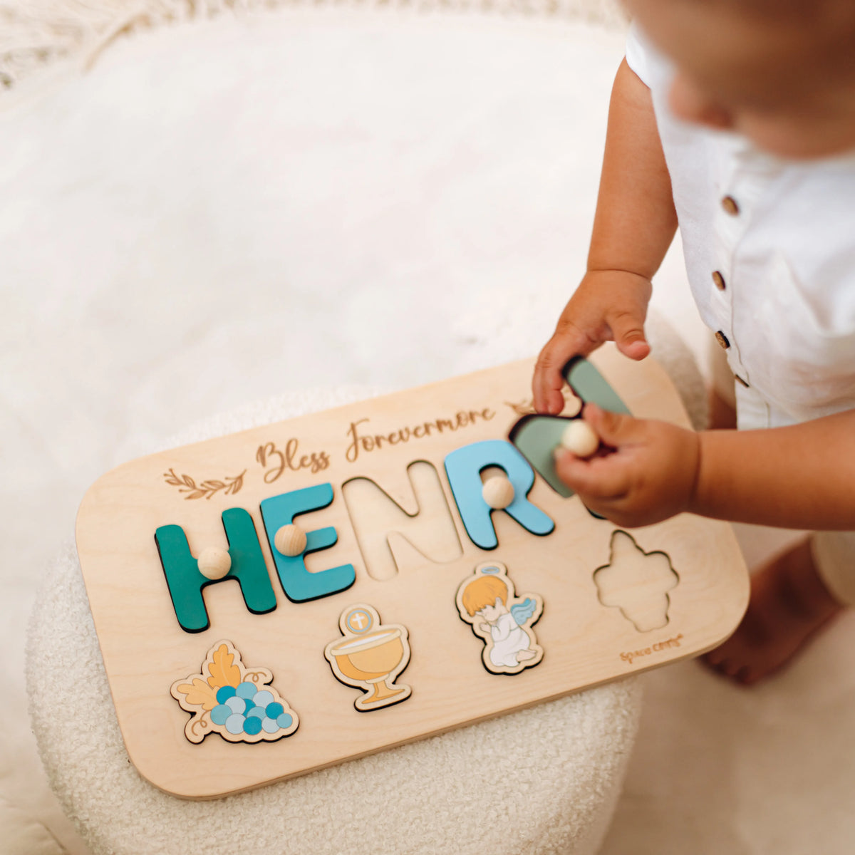 Toddler playing with wooden piece from personalized Henry baptism puzzle