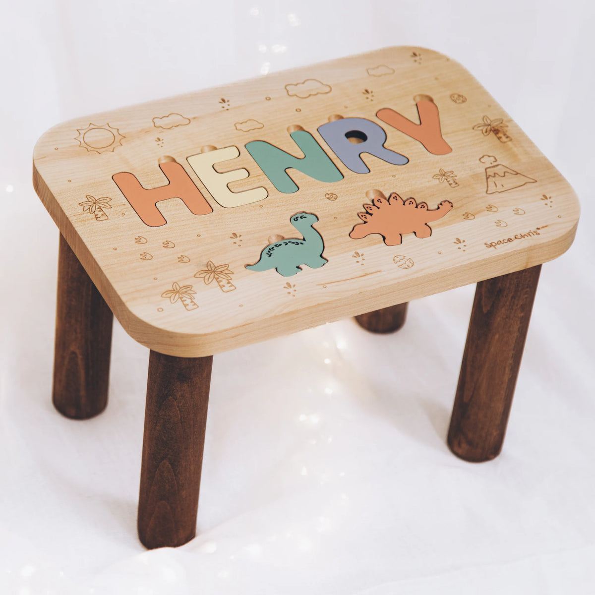 Personalized wooden toddler step stool featuring the name Henry and painted dinosaur puzzle elements.