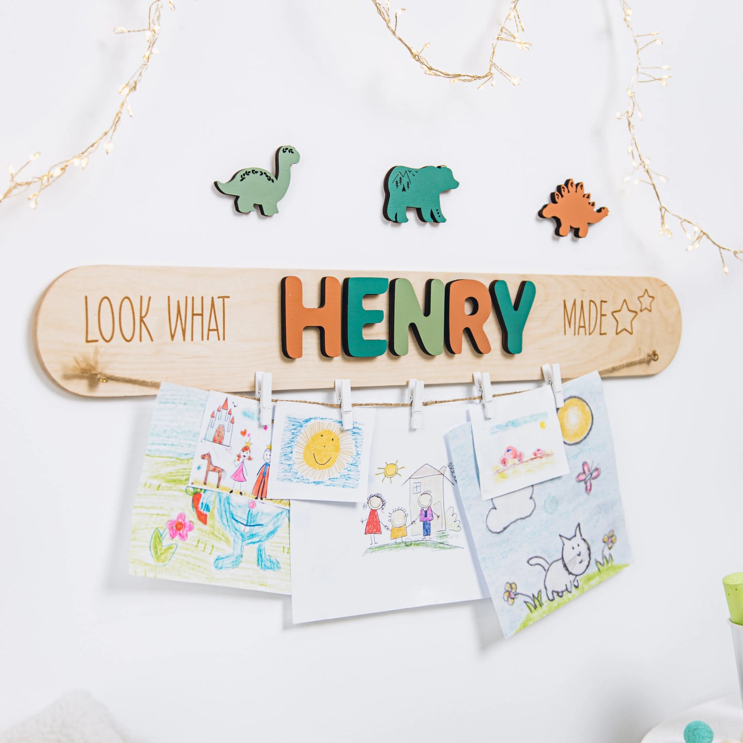 Wooden Look What I Made art display with the name Henry in green letters, holding children's drawings with clips and dinosaur pieces