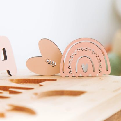 Close up of chunky painted wooden cutout elements on a personalized name puzzle stool.