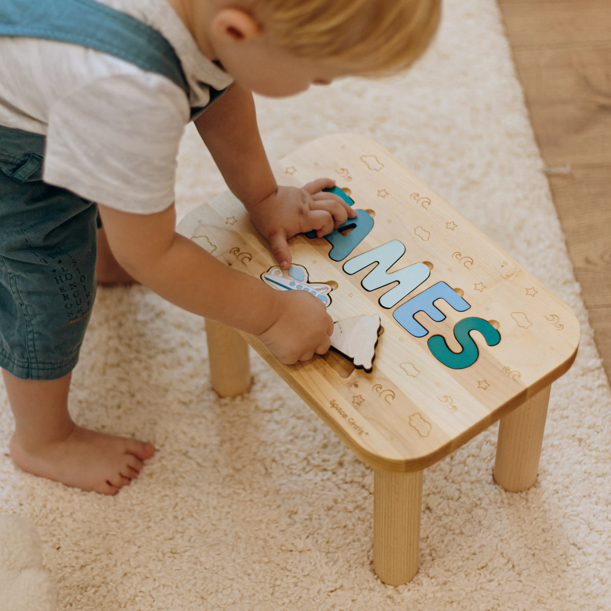 Little boy assembling the printed puzzle elements on his personalized Montessori toddler step stool.