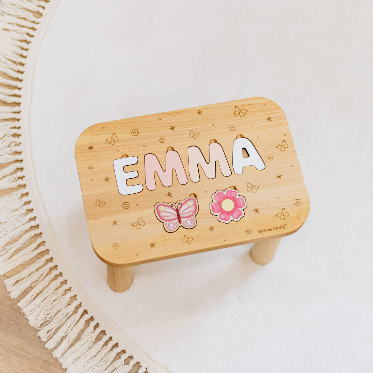 Top view of a beautiful custom toddler step stool with the name Emma resting on a nursery rug.