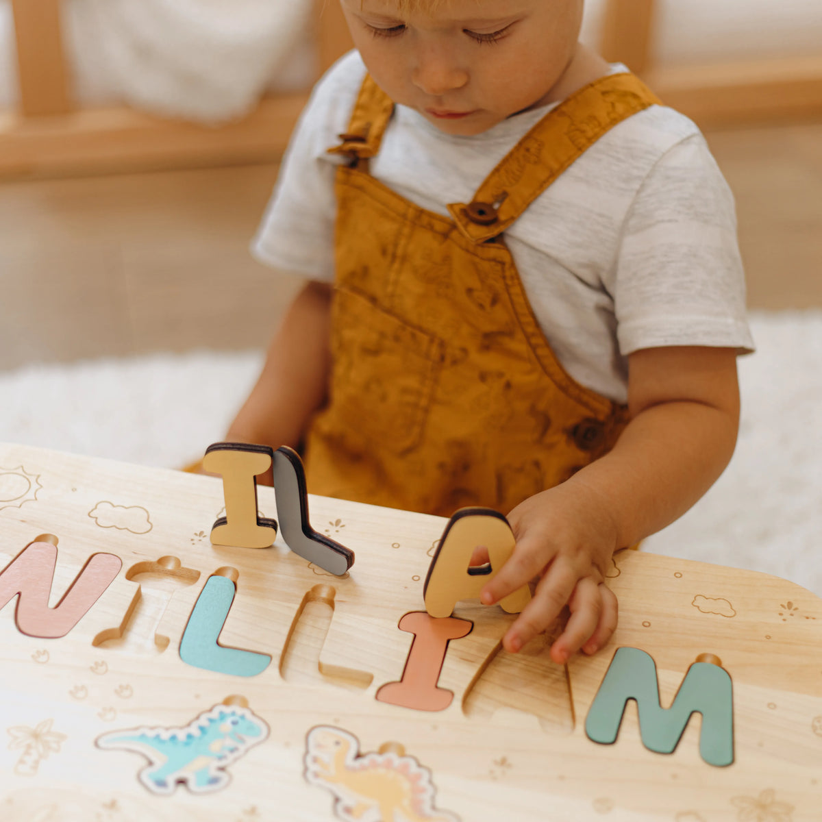 Close up of a toddler playing with chunky wooden letters on his custom name puzzle step stool.