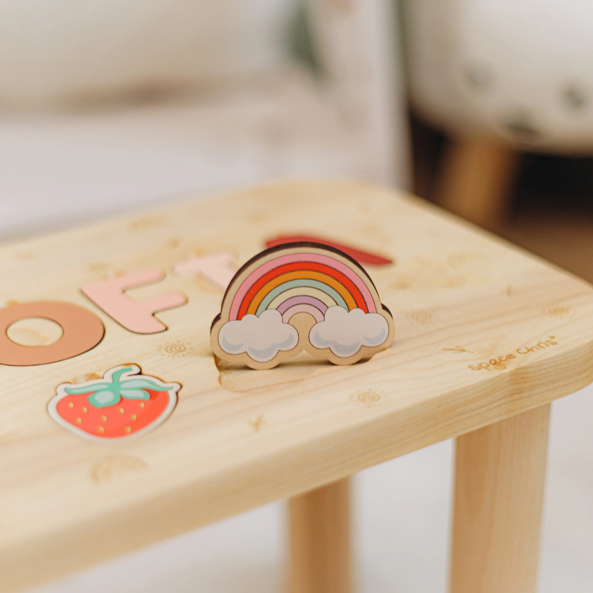 Close up of printed Boho theme rainbow and strawberry puzzle elements on a custom wooden name stool.