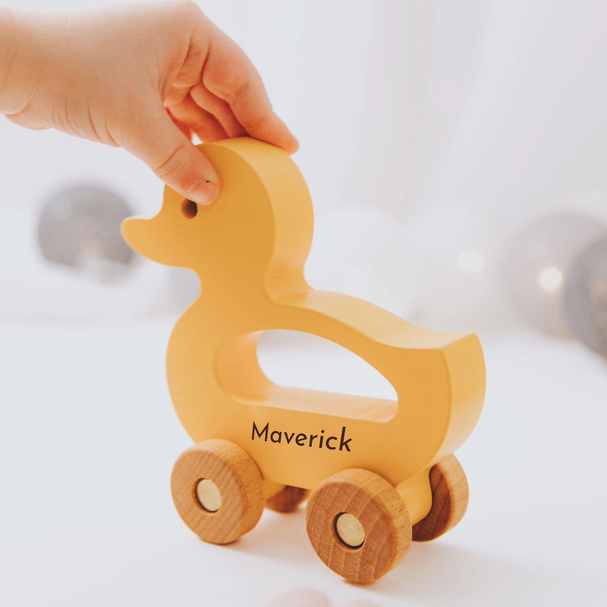 Close-up of personalized yellow wooden duck toy with name Maverick