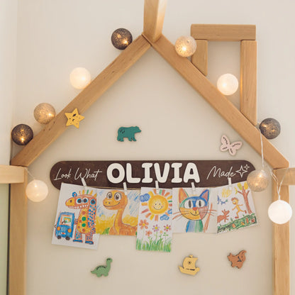 Wooden Look What I Made sign with the name Olivia in a house-frame bed nursery with fairy lights