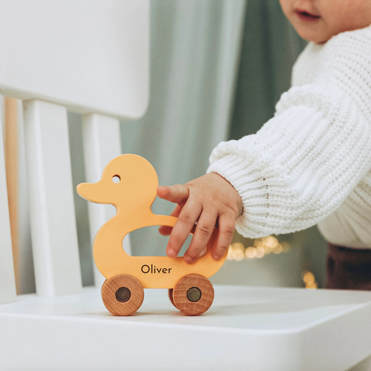 Baby pushing personalized light wood duck toy with name Oliver