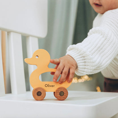 Baby pushing personalized light wood duck toy with name Oliver