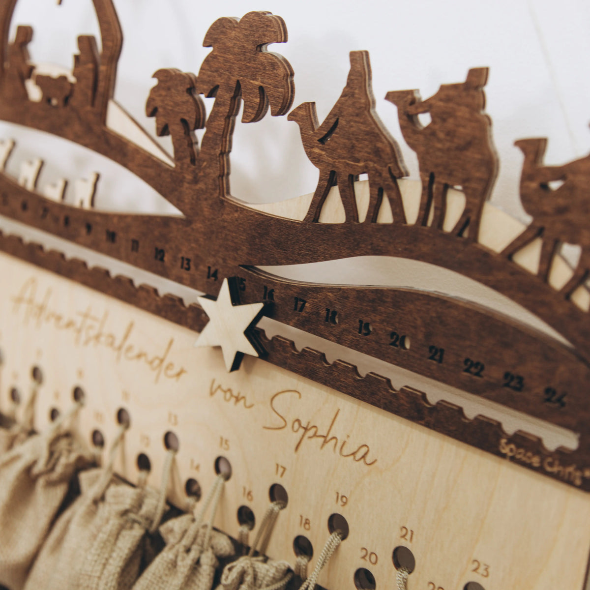 Close-up of wooden Nativity advent calendar with camels, palm trees and personalized name