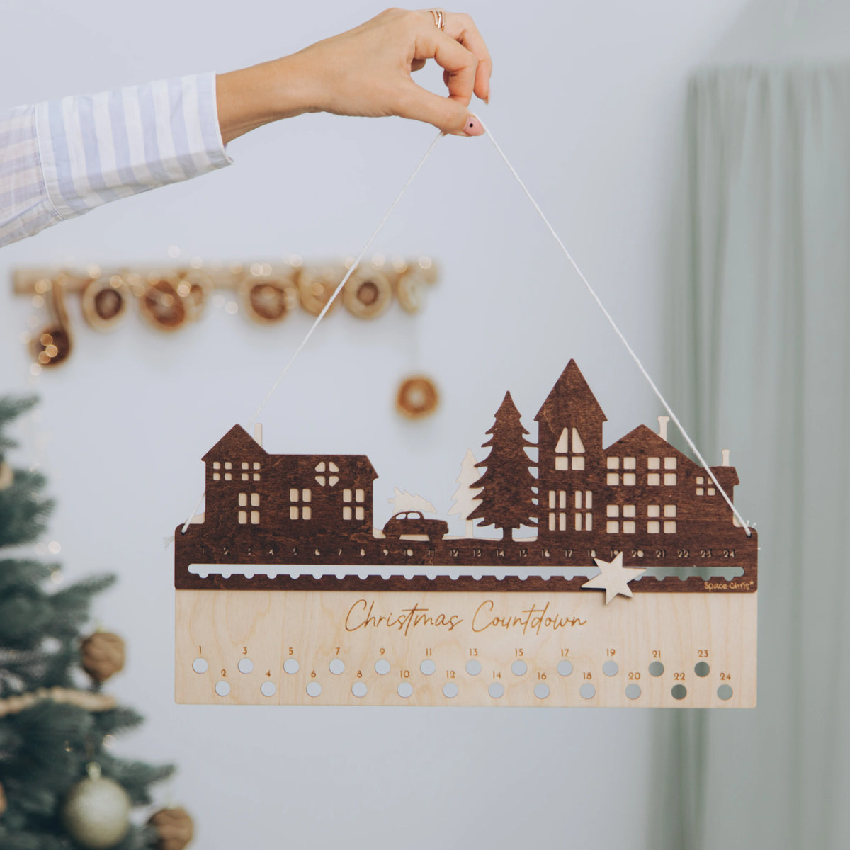 Hand hanging a personalized wooden City design advent calendar on the wall