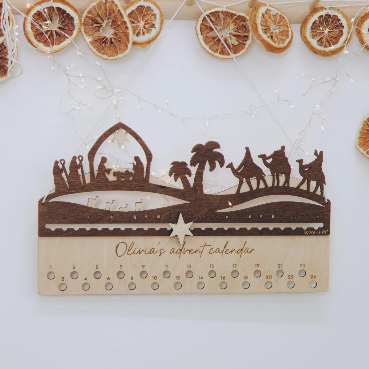 Wooden Nativity advent calendar decorated with a dried orange garland and personalized name