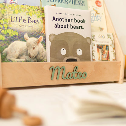 Light wood personalized bookshelf with name Mateo in green wooden letters and front-facing children's books