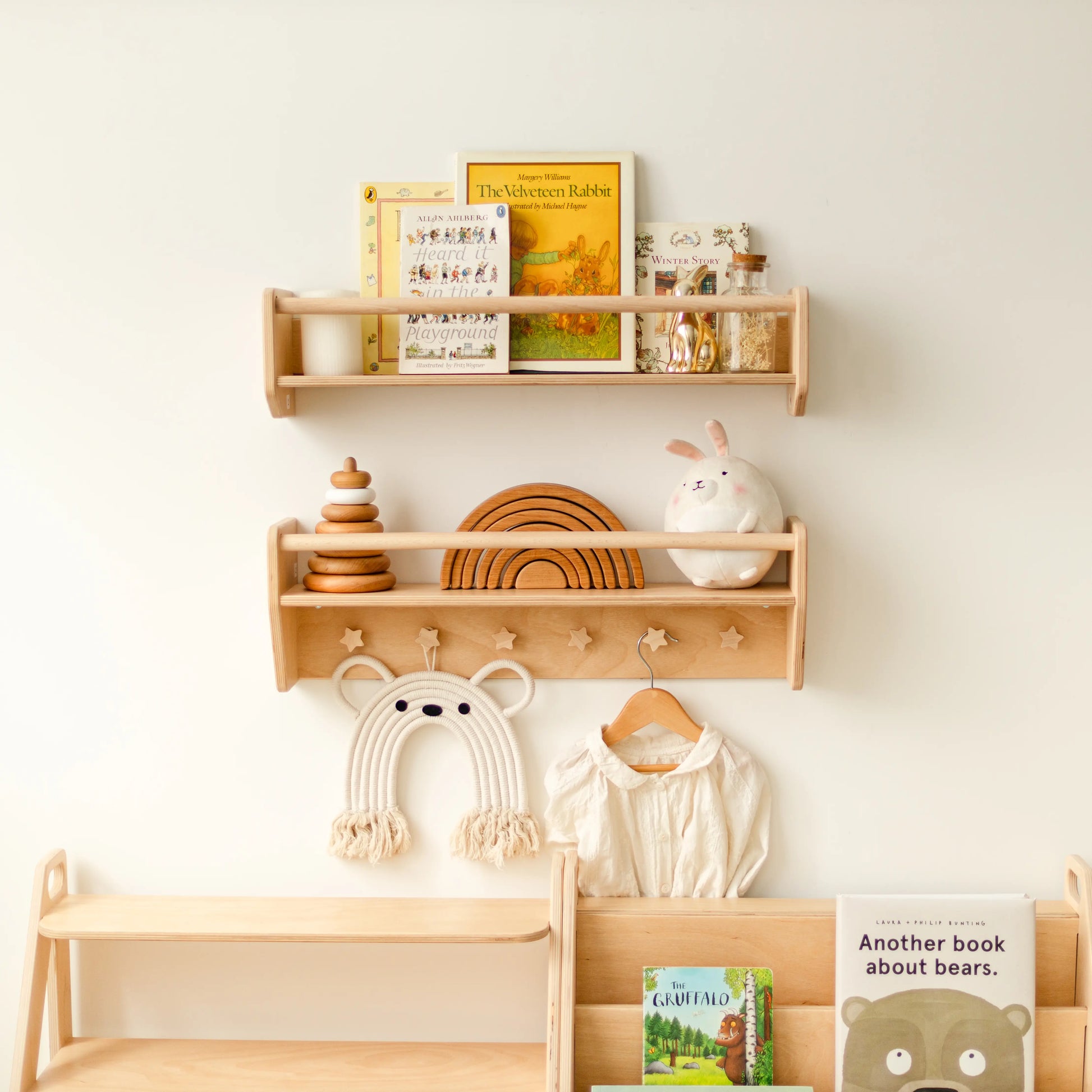 Light wood nursery wall shelves with children's clothes hanging from star-shaped wooden pegs