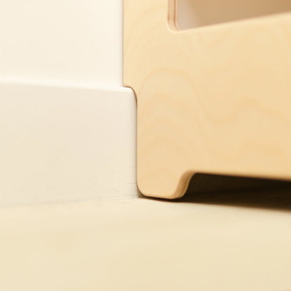 Close-up of the smooth rounded edge of a wooden Montessori bookshelf, showing the child-safe finish