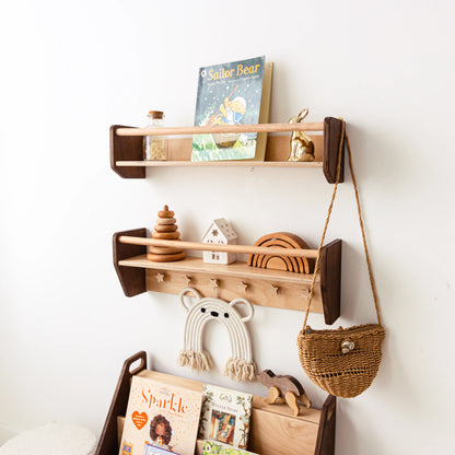 Dark wood wall shelf set with picture books, toys and a woven bag on star-shaped pegs