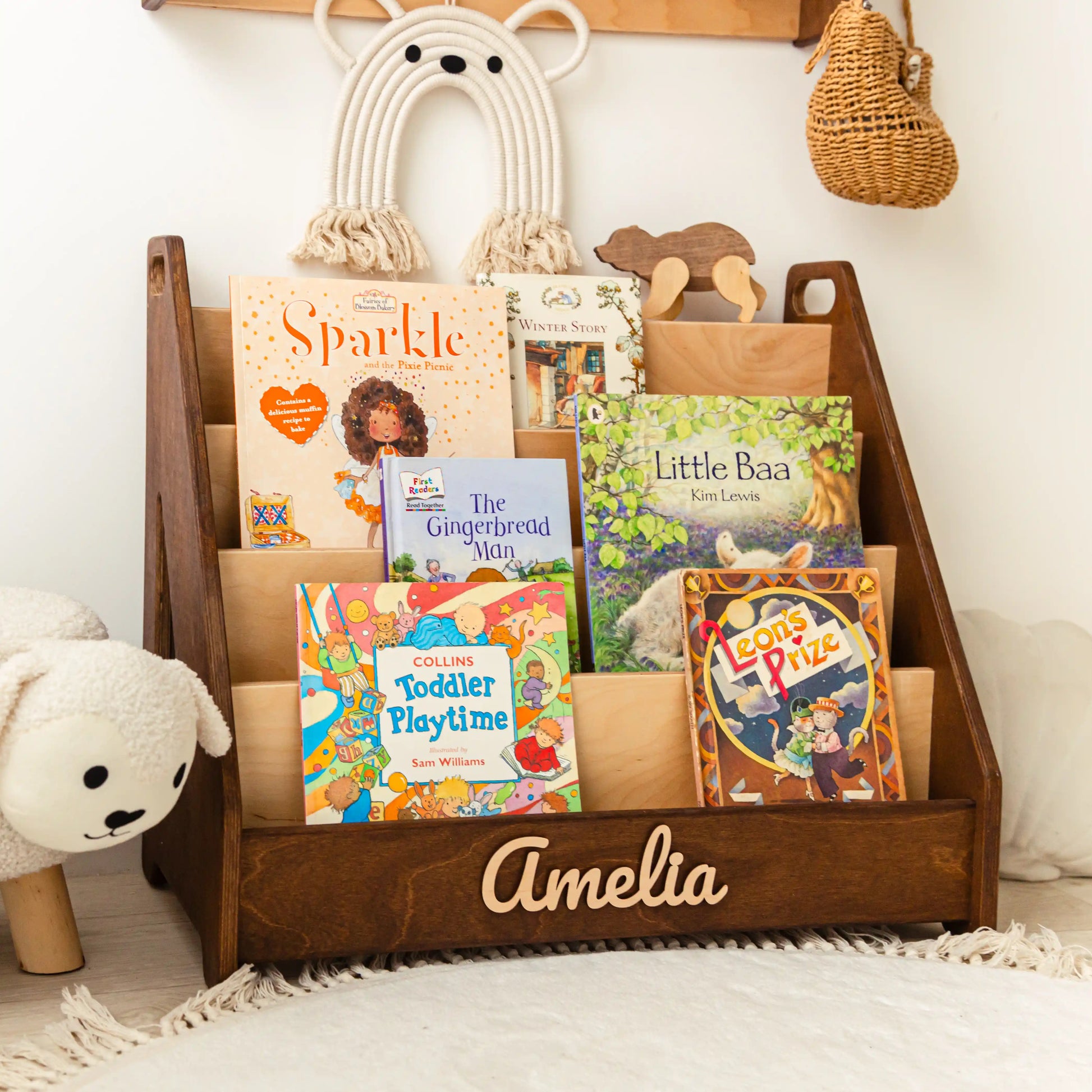 Dark wood personalized bookshelf with name Amelia, teddy bear and macrame in a cozy nursery corner
