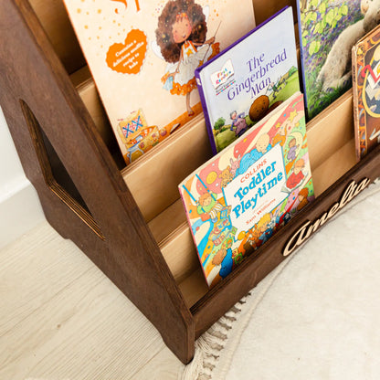 Close-up of dark wood front-facing bookshelf tiers filled with colorful kids' books