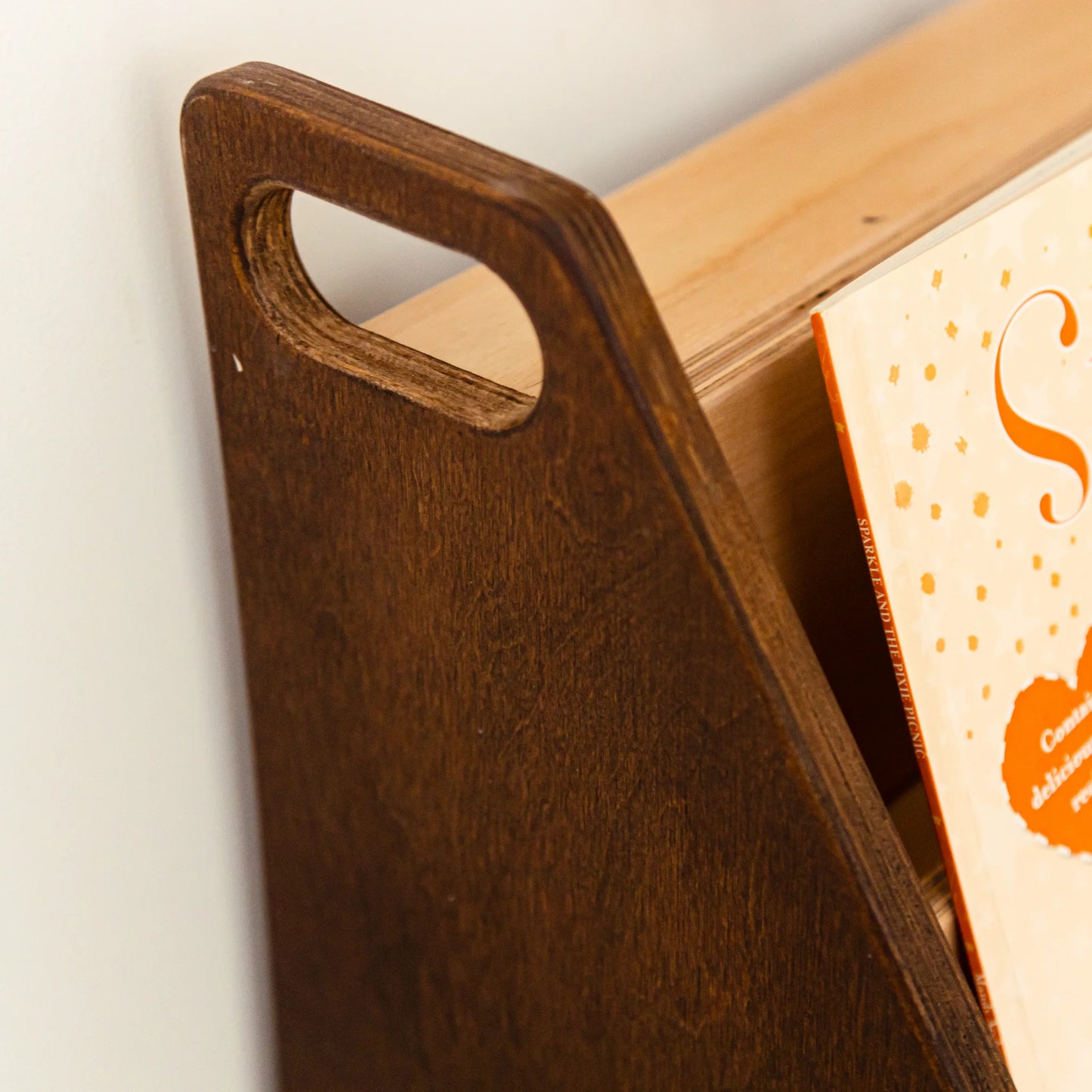 Close-up of the dark wood bookshelf side panel with a cut-out carry handle
