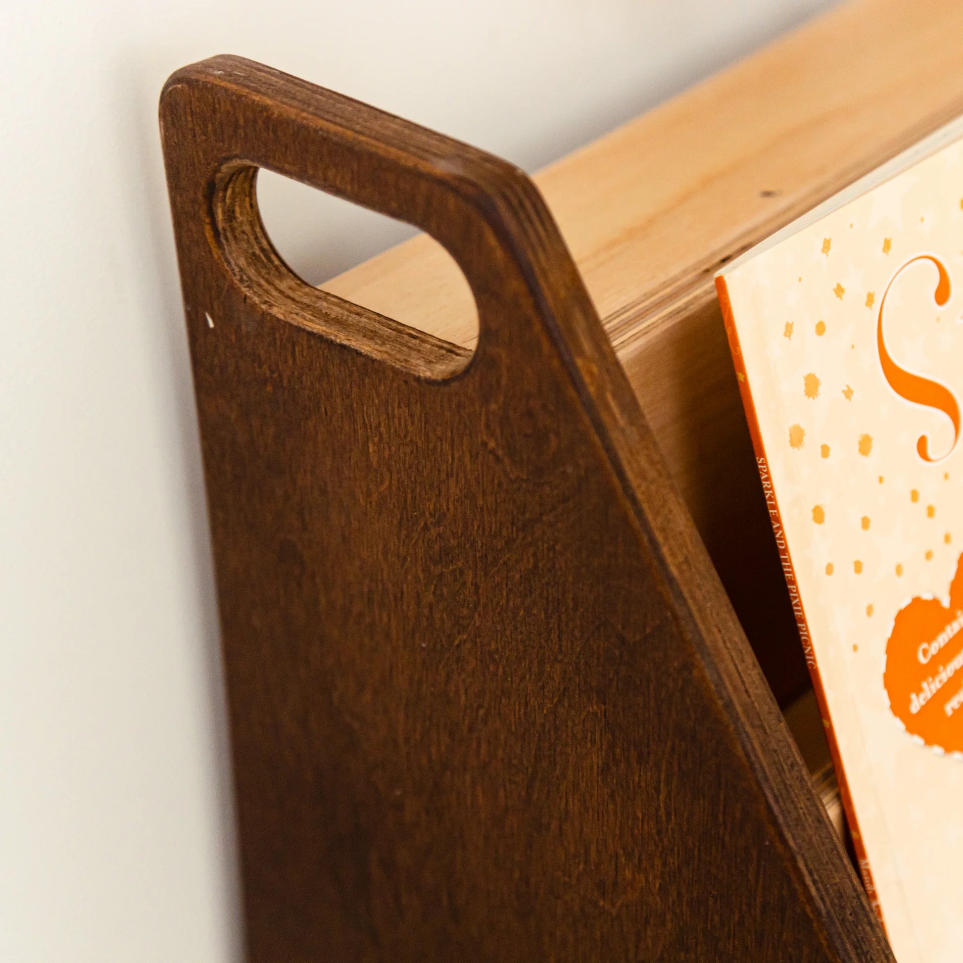 Close-up of the dark wood bookshelf side panel with a cut-out carry handle
