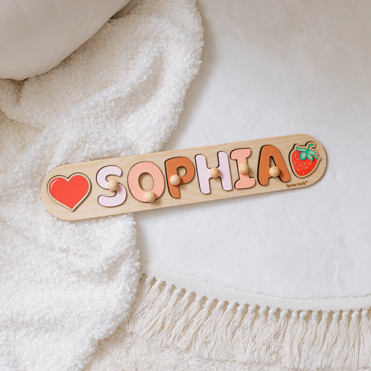 Name puzzle with the name Sophia and a heart piece on a white blanket