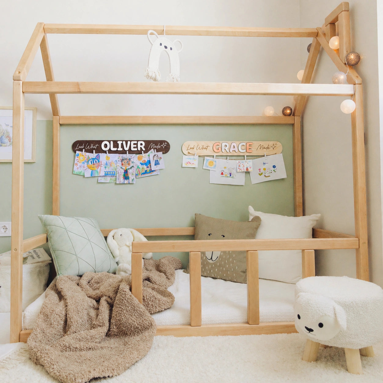Look What I Made name signs with clipped artwork above a Montessori floor bed in a kids room