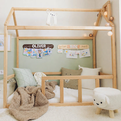 Look What I Made name signs with clipped artwork above a Montessori floor bed in a kids room